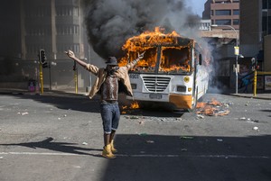 Photo of man standing in front of burning bus