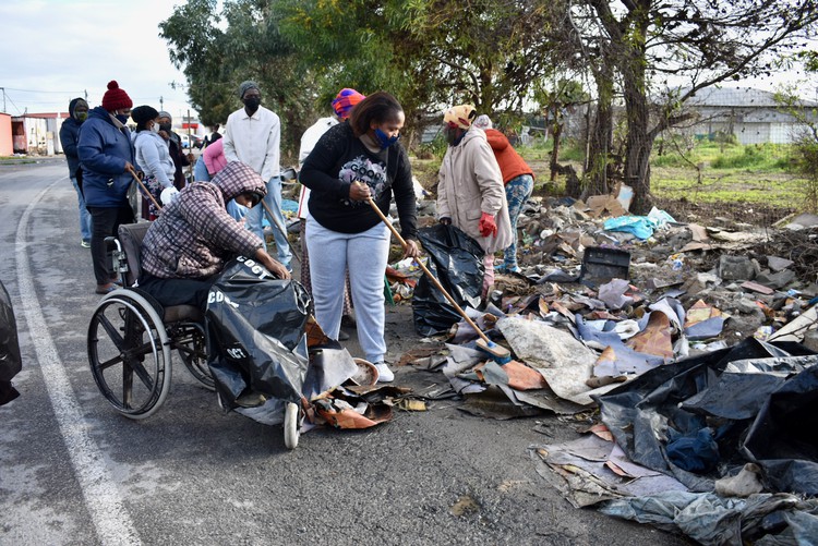 Photo of people, one in a wheelchair, cleaning up rubbish