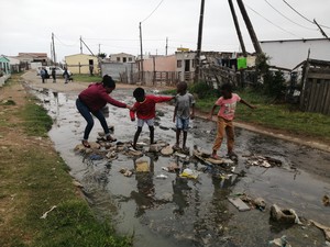 Photo of people crossing stream of sewage