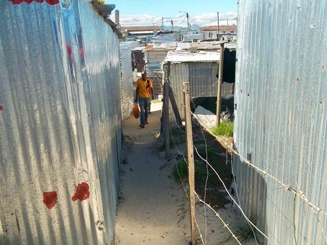 Photo of a man walking between shacks