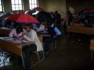 Photo of students holding umbrellas above their heads in a classroom