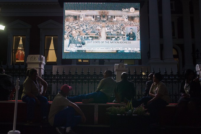Photo of people watching large TV screen