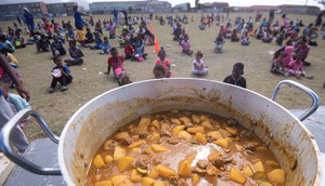 Photo of a soup pot with children in a field in the background