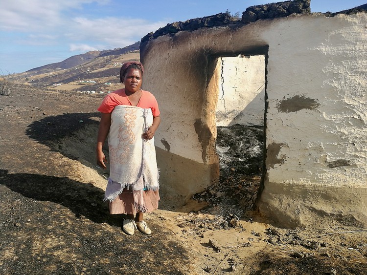 Photo of a woman in front of a burnt out house