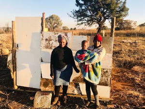 Photo of mother and daughter next to shack