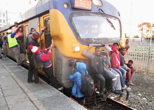 Photo of train with people hanging on its front