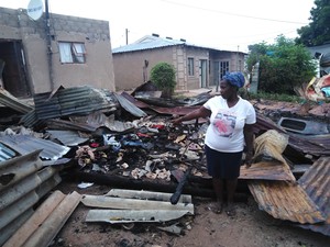 Photo of the mother standing in the middle of her charred shack