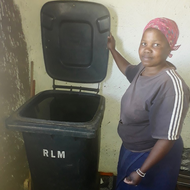 Photo of a woman holding up the lid of a black bin