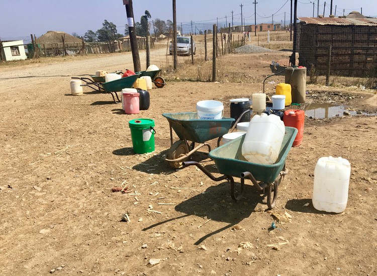 Photo of wheeelbarrows and plastic water containers