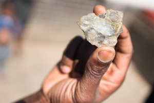 Photo of hand holding piece of rock containing gold