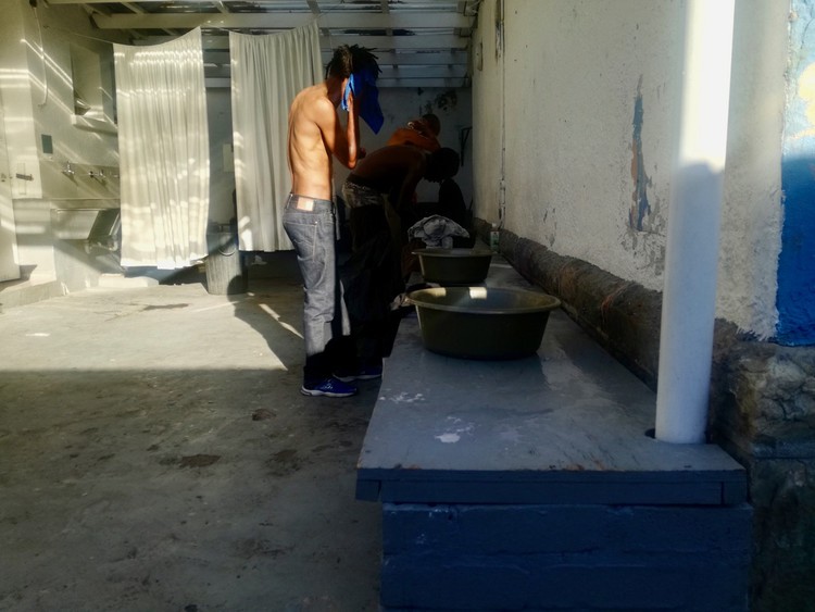 Photo of a man washing himself from a bucket