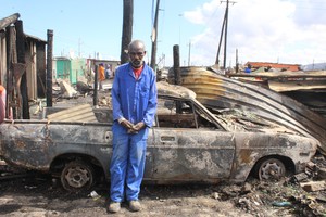 Photo of man in front of burnt car