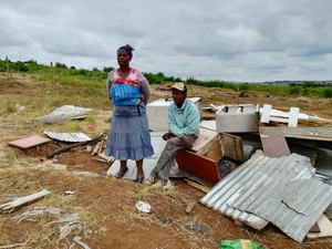 Photo of two people with a demolished shack