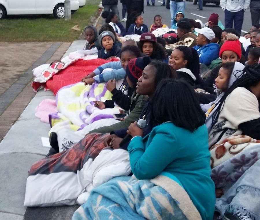 Photo of students sitting on a pavement